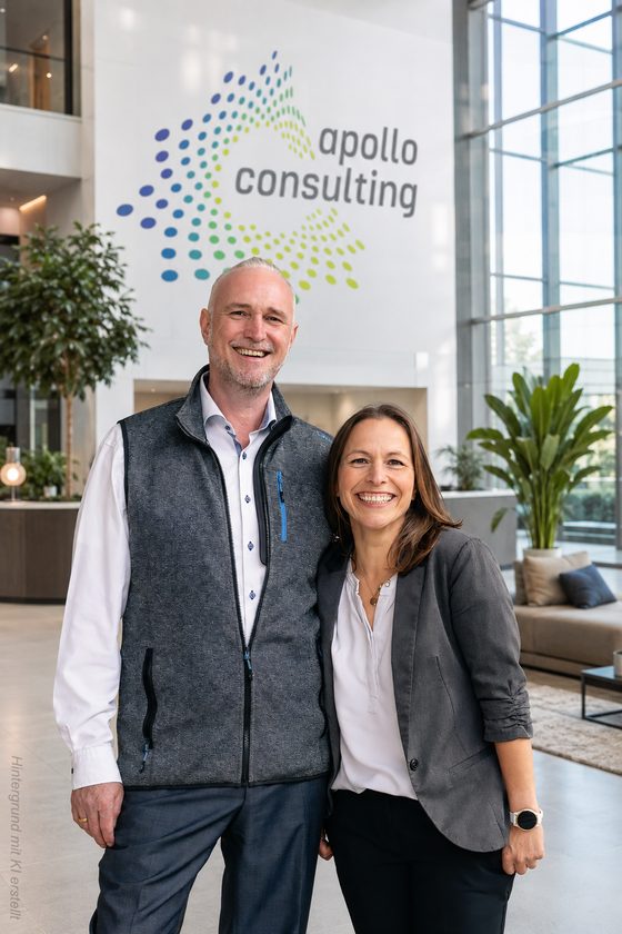 Volker Loibl und Melanie Reuß von apollo consulting vor der Logo-Wand im Büro