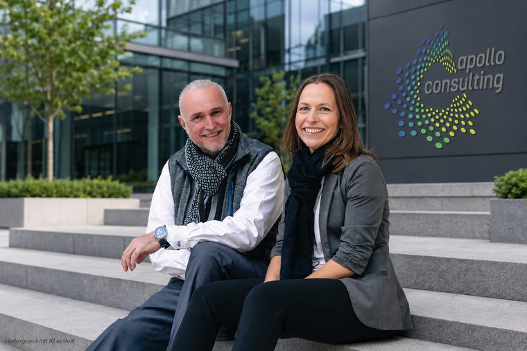 Volker Loibl und Melanie Reuß sitzen auf den Treppenstufen vor dem Büro von apollo consulting