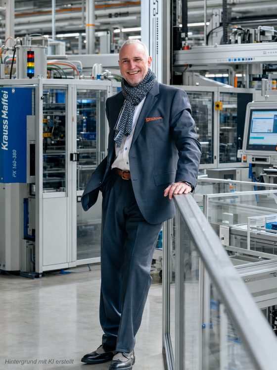 Volker Loibl, Gründer von apollo consulting, an der Brüstung einer Fertigungshalle mit Spritzgießmaschinen